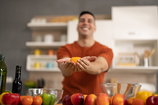 A homely and healthy male prepares nutritious diet, including variety of fruits. Following cooking show on laptop Mastery of peeling, chopping, and slicing fruits to prepare them in artistic style.