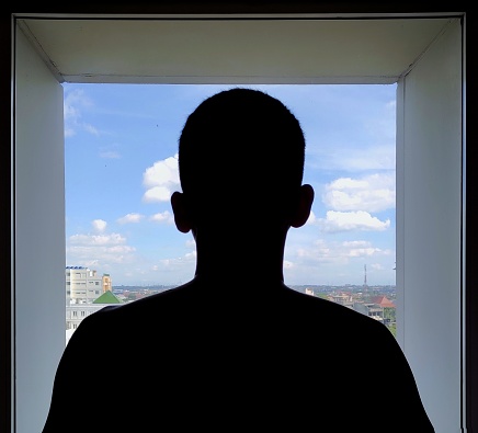 silhouette of a man looking at the view through the window