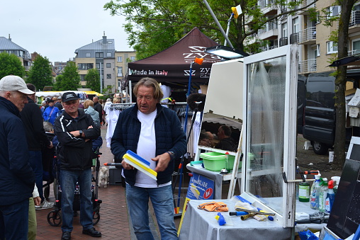 Blankenberge, West-Flanders, Belgium - May 22, 2023: market vendor demonstrates washing windows with a practical wiper