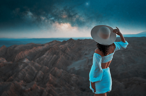 rear view portrait woman standing on the Moon Valley looking at Milky Way over the desert in San Pedro de Atacama