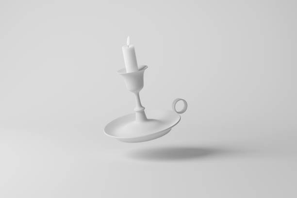 Lighting candle in a brass candlestick on the table against the background of a window with tulle