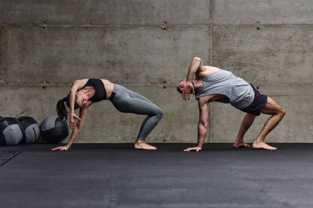 An attractive couple in the gym engaging in various stretching exercises together, showcasing their dedication to fitness, flexibility, and overall wellbeing. With synchronized movements, they demonstrate coordination, balance, and endurance while supporting and motivating each other on their fitness journey. una pareja atractiva en el gimnasio participando en varios ejercicios de estiramiento juntos, mostrando su dedicación al fitness, la flexibilidad y el bienestar general. con movimientos sincronizados, demuestran coordinación, equilibrio y resistencia mie
