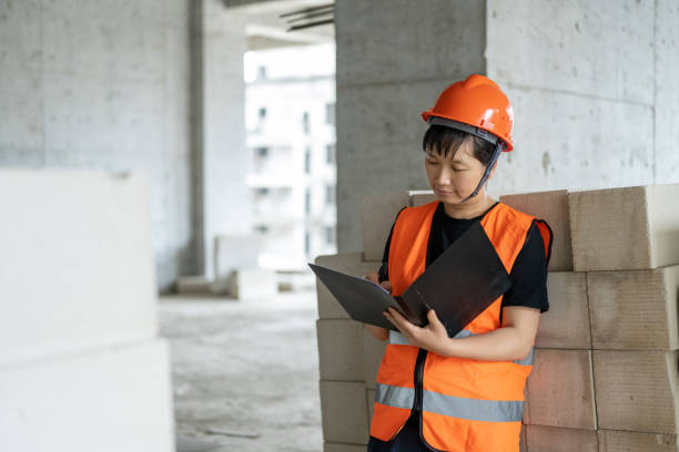 una trabajadora de la construcción trabaja en un sitio de construcción de edificios - blueprint construction worker real estate new fotografías e imágenes de stock