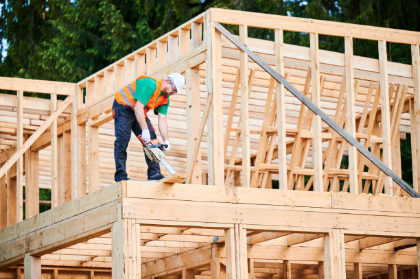istock Carpenter using circular saw for cutting wooden plank while building wooden frame house. 1492639553
