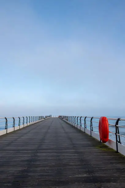 An empty pier in the North Yorkshire seaside town of Saltburn-by-the-Sea on a misty day.