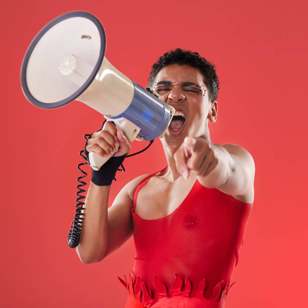 anger, gay and portrait of a man with a megaphone isolated on a red background in a studio. decision, freedom and person shouting and talking into a speaker while pointing with choice on a backdrop - sex and reproduction audio imagens e fotografias de stock