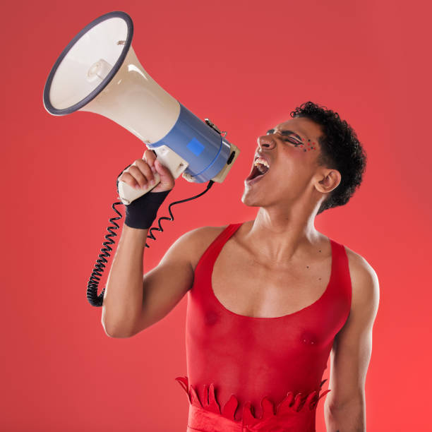 anger, gay and a man with a megaphone for protest isolated on a red background in a studio. lgbt, freedom and person shouting and talking into a speaker for gen z rights and voice or riot on backdrop - sex and reproduction audio imagens e fotografias de stock