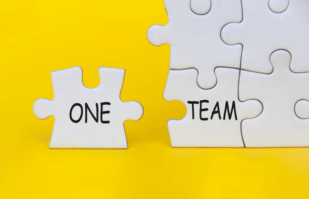 istock One Team text on separated jigsaw puzzle on yellow background. Teamwork concept 1492644822