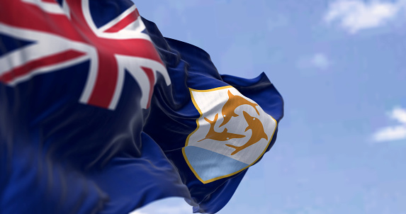 Anguilla Flag waving in the wind on a clear day. Blue Ensign with British flag in canton, coat of arms, three dolphins on white shield. 3d illustration render. Selective focus. Fluttering fabric