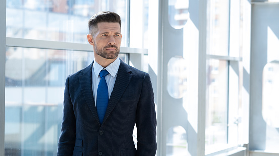 Mid adult businessman standing in office looking aside