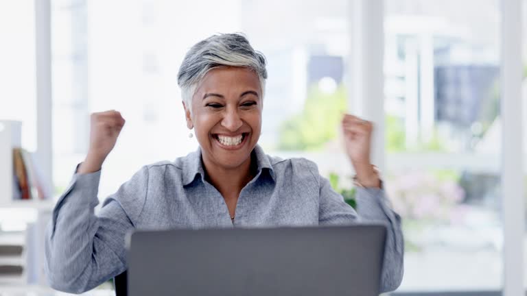 Senior woman, laptop and office with celebration, happiness and surprise with winning, goals or achievement. Indian executive, applause and computer with wow, celebrate or yes for stock market profit