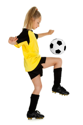 Full length side view of eight year old girl with soccer ball, isolated on white background.
