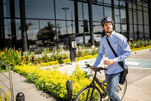 Young man walking with bicycle looking around outdoors