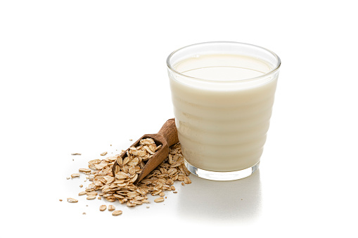 Glass of healthy vegan oat milk on white background