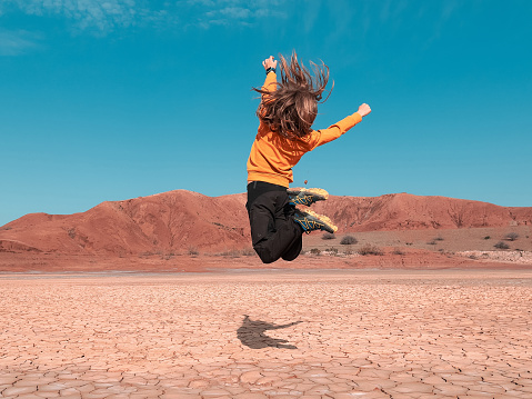 Boy jumping in desertic landscape- Morocco
