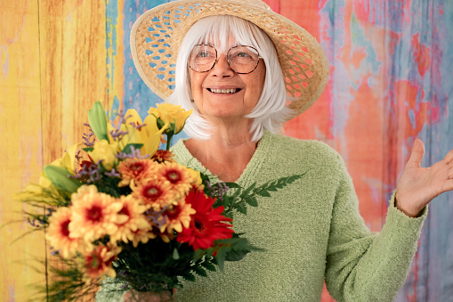 Happy white-haired senior woman receiving a bouquet of flowers. Valentine's Day Women's Day birthday holiday party.