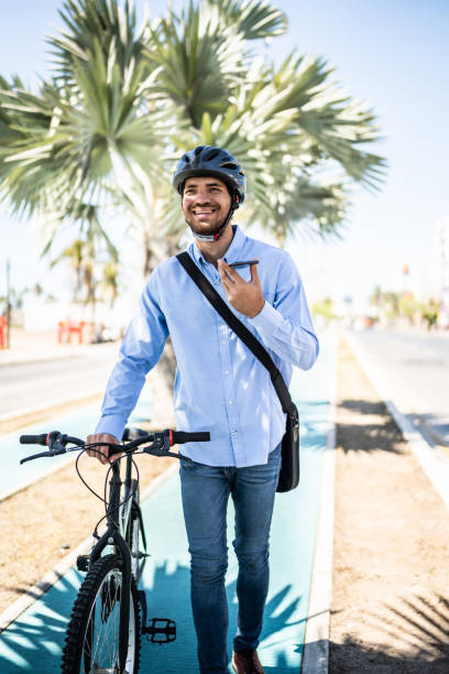 istock Young man using mobile phone sending audio message while walking with bicycle outdoors 1492656702