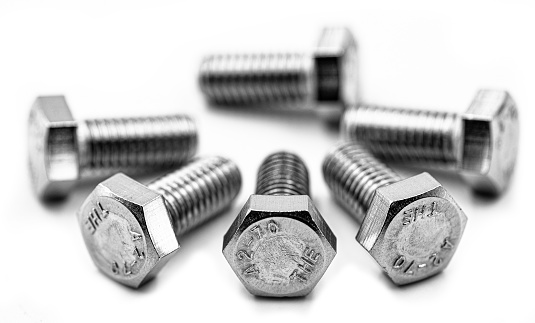 Stainless steel bolts and screws arranged on white background.