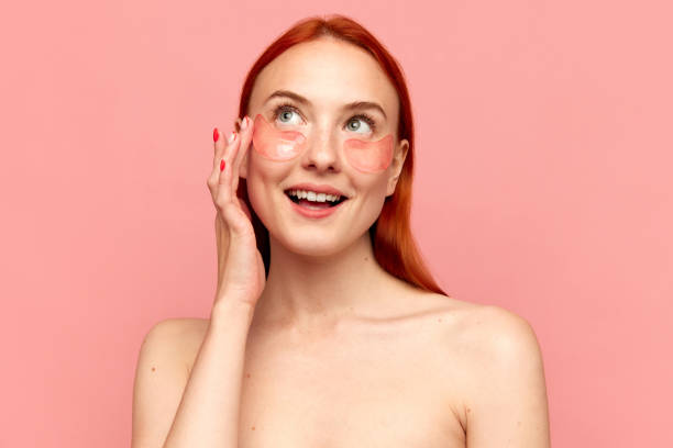 istock Portrait with young charming girl with bare shoulders using eye patches for skin refreshing over pink background. Morning beauty procedure 1492657151