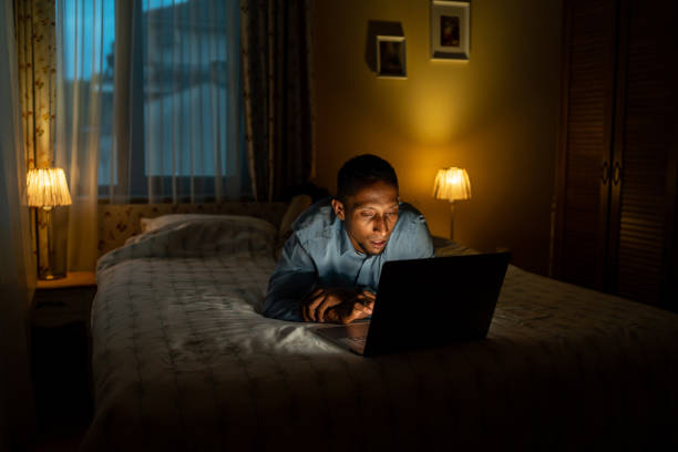 istock Man lying on bed reading his laptop at night 1492659588
