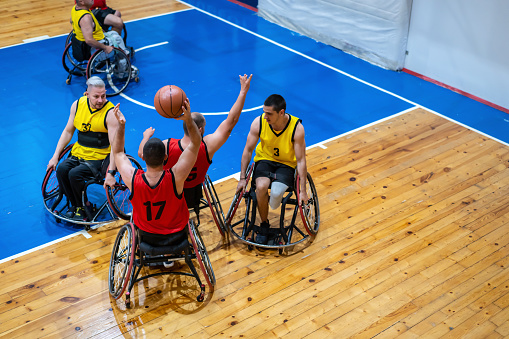 Looking down to wheelchair athletes playing basketball in indoor basketball court