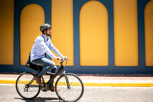 Young man riding bicycle wearing protecting helmet outdoors