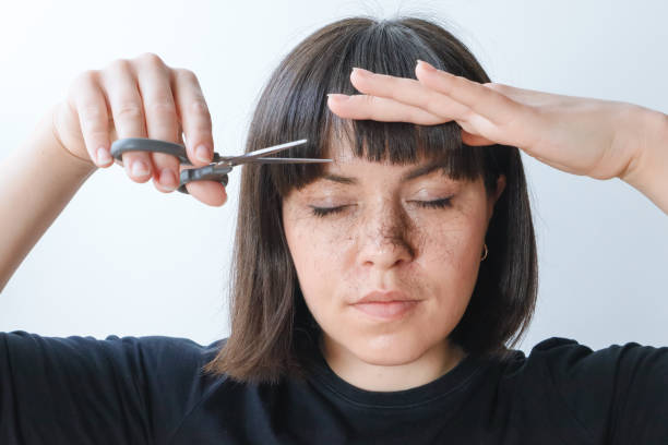 The girl cuts her bangs with scissors