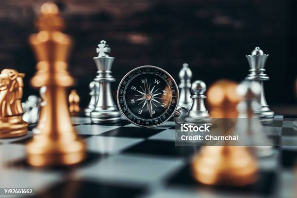 Compass Leaning Against Chess Piece With Other Chess Pieces In