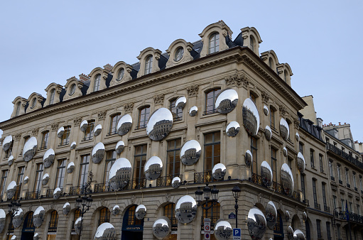 Paris, France - March 16, 2023: Many mirrors rounded reflecting the buildings around it on Luxury store facade in the first district of Paris, France