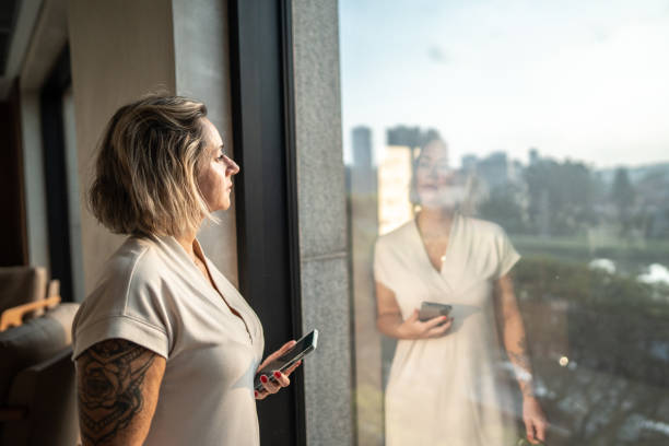 istock Contemplative mature woman looking through the window 1492668086