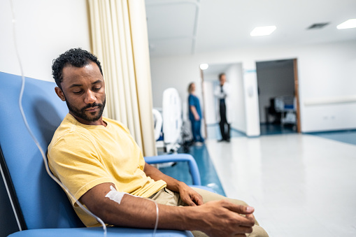 Mid adult man taking IV drip in the hospital