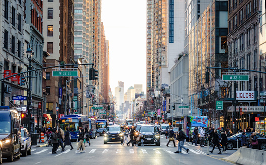 New York City, USA - Pedestrians walking on a crosswalk as traffic waits on the street in Midtown Manhattan.
