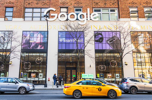 New York City, USA - A yellow taxi passing people on the sidewalk outside Google's large store and office in the Port Authority Building in Manhattan.