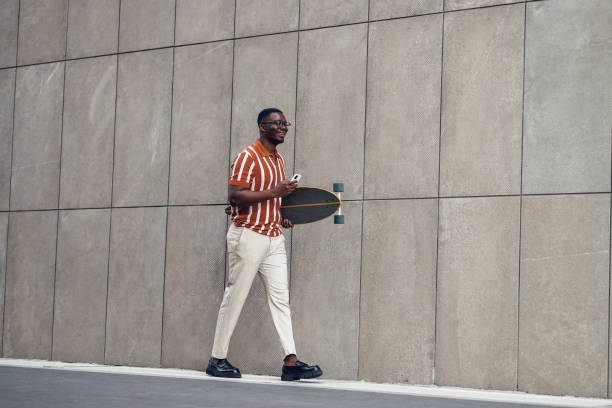 istock Young urban African American man walking and carrying longboard 1492674251