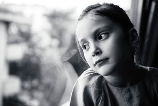 Portrait of a preschool age girl looking through window.