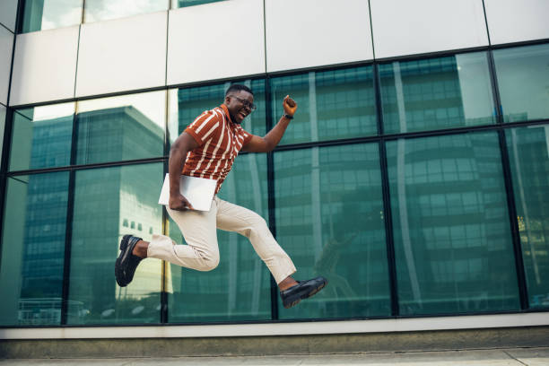 istock Happy young businessman jumping with laptop 1492675529