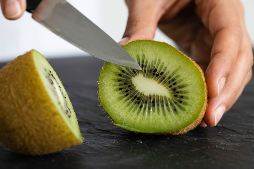 A woman cutting kiwi.