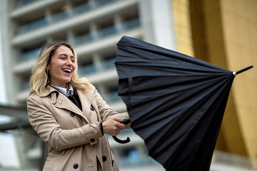 Happy businesswoman opening her umbrella in the rain