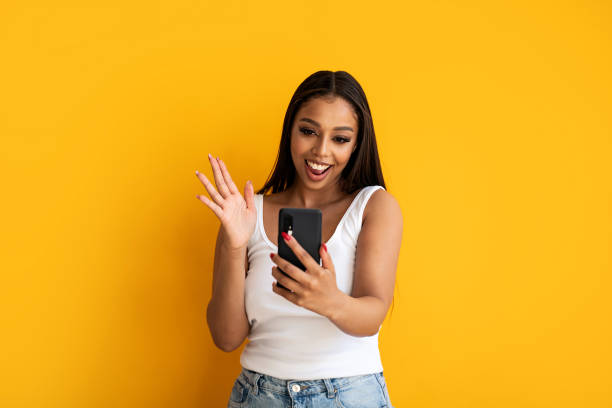 istock Young happy woman wearing basic clothes smiling to the cellphones empty screen, posing over yellow studio background. Real people emotions. 1492677309