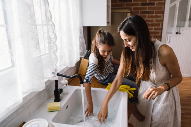 istock Mother and child having fun and playing while washing dishes in the kitchen 1492677598