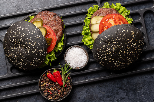 Homemade beef burgers with black buns. Flat lay