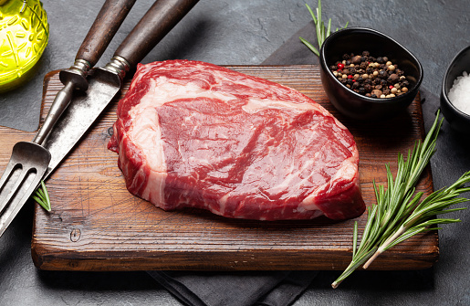 Raw ribeye steak on cutting board. Barbecue cooking