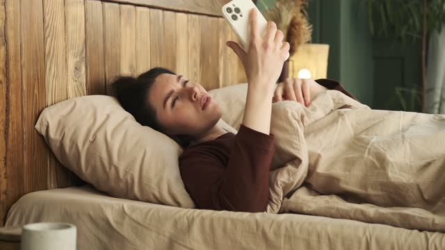Upset Woman in Pajamas turns off Alarm on Phone