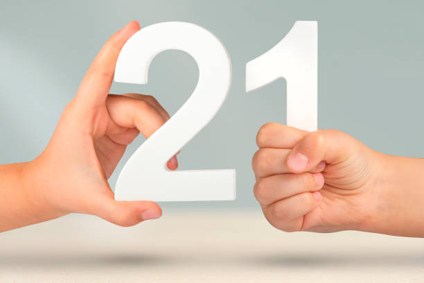 istock Number two one in hand. Hand holding white number 21 on blurred background with copy space. Concept with number twenty one. 21 percent, birthday 21, twenty one 1492684229