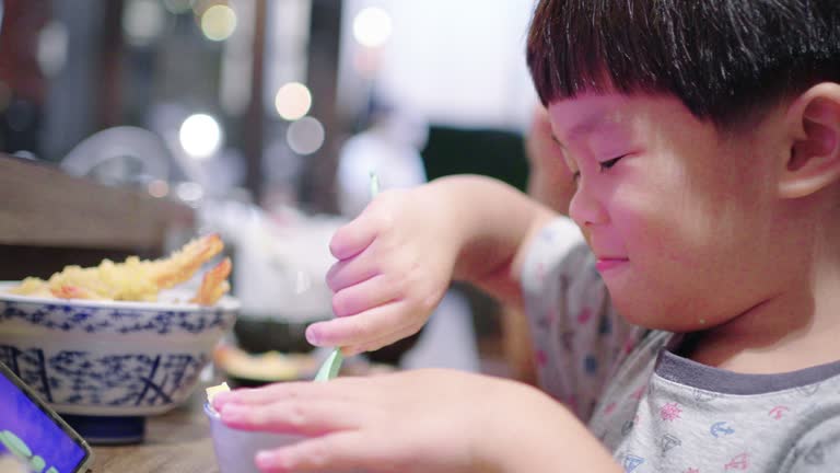 Asian little boy eating Japanese food at the Japanese restaurant.