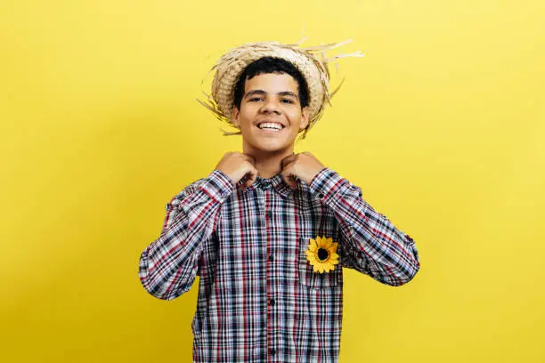 Photo of Brazilian teenager boy wearing typical clothes for the Festa Junina on color background