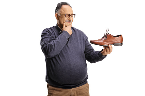 Mature man holding an elegant brown leather shoe and thinking isolated on white background