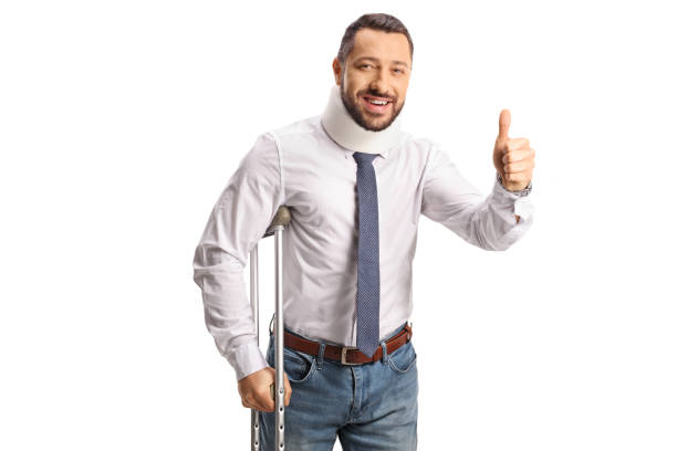 cheerful injured man with a cervical collar and a crutch gesturing thumbs up - physical injury men orthopedic equipment isolated on white imagens e fotografias de stock