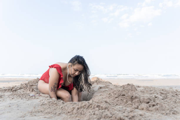 istock A young Hispanic woman is digging a hole in the beach 1492688892