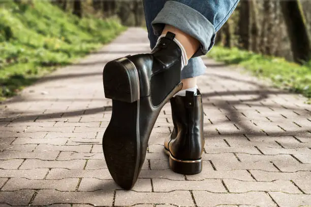 Close up of female legs in blue jeans and black leather chelsea boots.